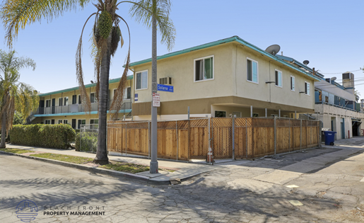 A building with a blue sign on the front is surrounded by a wooden fence.